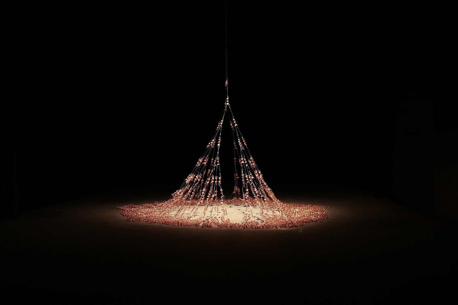 Mitt genetiske anker — suspended cascade of 1023 hand-woven copper spirals, spotlit in a dark room